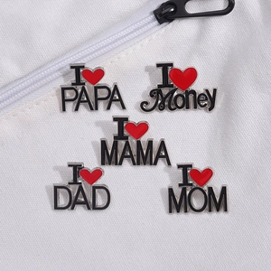 Détail macro de cinq broches cœur en émail avec gravure de lettres sur toile blanche