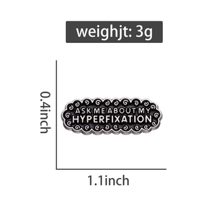 Detailed view showing dimensions of black enamel pin with Ask Me About My Hyperfixation text
