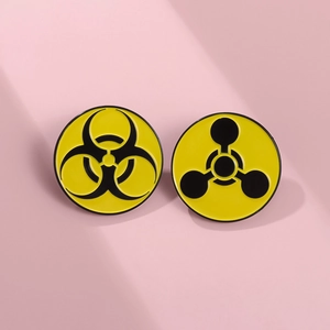 Detail of round enamel pins with yellow and black biohazard and chemical warning signs