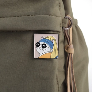 Detail of artistic cat enamel pin inspired by Girl with a Pearl Earring on a green bag