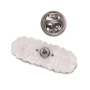 Macro shot of silver metal brooch back showing textured finish and butterfly clasp