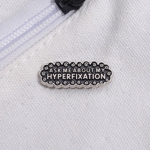 Creative black enamel pin with Ask Me About My Hyperfixation text on white canvas bag