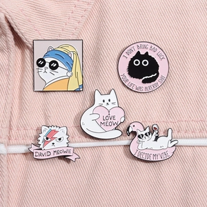 Detailed view of five creative cat enamel pins with artistic designs on pink denim fabric