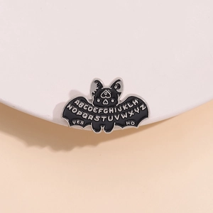 Gothic bat enamel pin with Ouija board lettering design on black metal wings