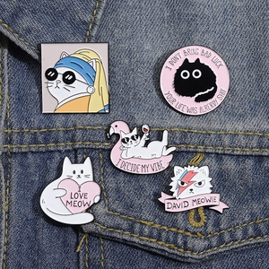 Close-up of five colorful cartoon cat enamel pins displayed on a blue denim jacket pocket