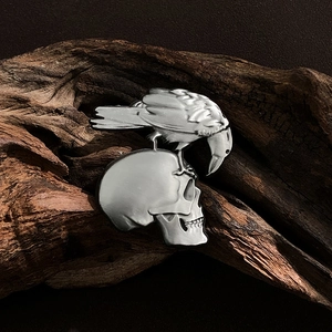 Macro detail of a gothic punk silver raven on skull brooch with fine metallic textures