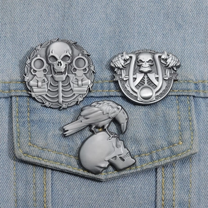 Detailed view of punk skull and crow metal pins pinned on light blue denim jacket pocket