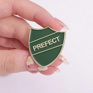 Minimalist shield enamel pin with green lacquer and gold Prefect lettering