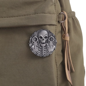 Close-up of vintage silver skull badge with revolvers and barbed wire on green fabric
