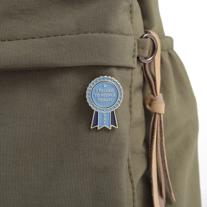 Detail view of a blue enamel award medal pin with gold edges on a fabric bag