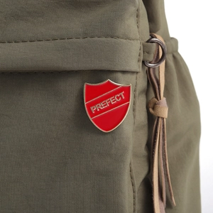 Close-up of red enamel shield badge with gold Perfect lettering on green fabric