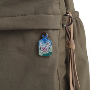 Nahaufnahme einer blauen Emaille-Flaschennadel mit Fee auf einer Stofftasche