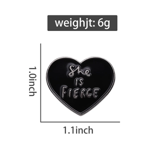 Detail of black heart enamel pin with She Is Fierce lettering and silver metal finish