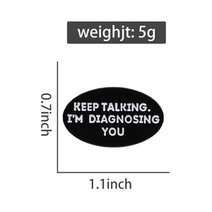Détail du badge en émail noir avec citation Keep Talking I'm Diagnosing You en blanc