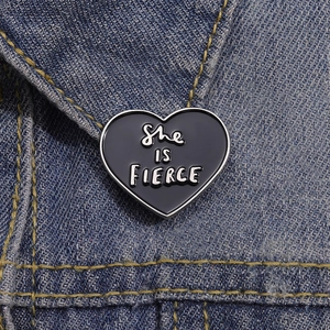 Black heart enamel pin with She IS FIERCE text on denim jacket collar