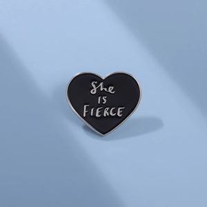 Spilla minimalista a cuore in smalto nero con scritta She Is Fierce su sfondo azzurro
