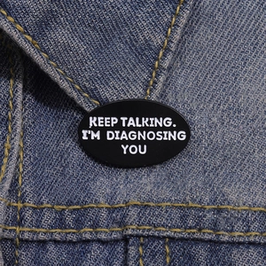 Funny black enamel pin 'KEEP TALKING I'M DIAGNOSING YOU' on a denim jacket collar