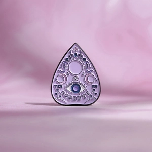 Macro view of purple planchette enamel pin with all-seeing eye and occult symbols