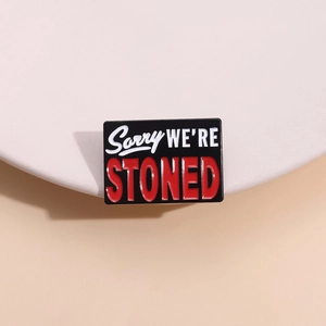 Emaille-Anstecknadel mit Sorry WE'RE STONED-Text in Schwarz und Rot auf weißem Ständer