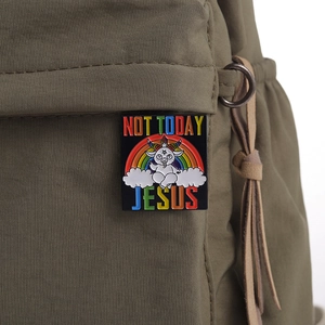 Rainbow 'NOT TODAY JESUS' enamel pin featuring a cartoon Baphomet on a green fabric bag