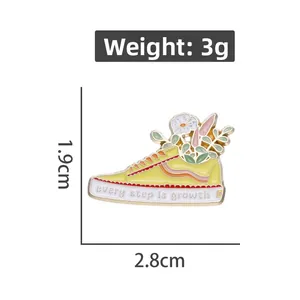 Detail of yellow sneaker enamel pin with flowers and every step is growth text