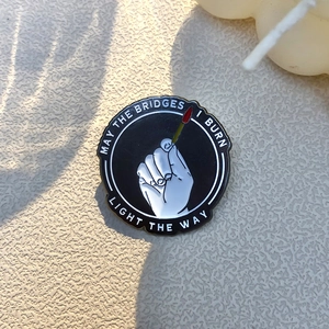 Zwarte ronde emaille pin met hand die lucifer aansteekt en motiverende Engelse tekst