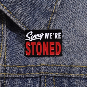 Retro Emaille Brosche mit Sorry We Are Stoned Aufdruck auf einer blauen Denim-Jacke