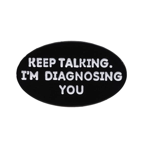 Oval black enamel pin with white text KEEP TALKING I'M DIAGNOSING YOU on white background