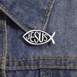 Silver Jesus fish metal brooch pinned on a blue denim jacket as a decorative accessory