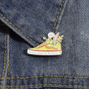 Canvas sneaker enamel brooch with floral details and every step is growth text