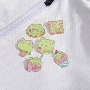 Set de 6 pines de esmalte de rana y postres con donut y tostada sobre un bolso de lona
