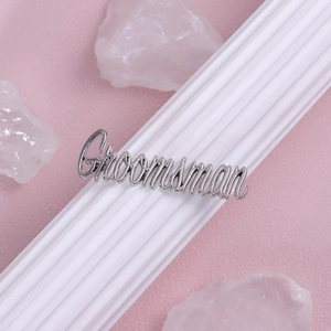 Detailed view of silver script Groomsman brooch pin on elegant textured background