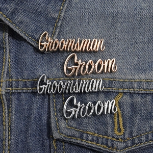 Macro shot of rose gold Groomsman and silver Groom script metal lapel pins on denim