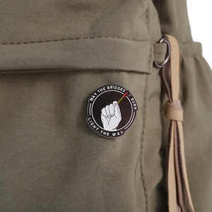 Gedetailleerde close-up van een ronde emaille broche op een groene canvas rugzak