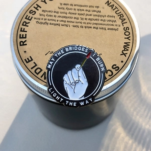 Zwarte emaille pin met brandende lucifer en inspirerende tekst May the bridges I burn light the way