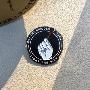 Klassieke emaille pin met handmotief en motiverende tekst in zwart en goud