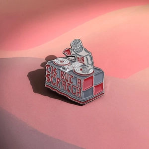Detail of knight DJ enamel pin featuring Tis But A Scratch text from Monty Python