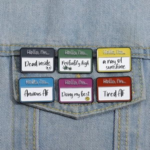 Group of six colorful enamel badges with quotes displayed on a blue denim jacket pocket