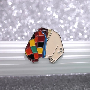 Macro detail of enamel jacket brooch featuring colorful patchwork and silver star accents