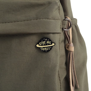 Détail du pin's émaillé Give Me Space avec design de planète sur un sac à dos en toile