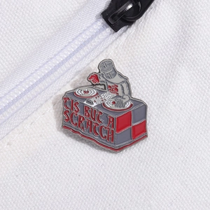 Enamel knight DJ pin with 'Tis But A Scratch' quote on white canvas background