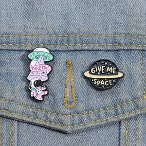 Detail von Cartoon Astronaut und UFO Emaille-Pins auf Jeansjacke mit Weltraum-Text