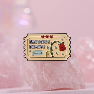 Detailed macro view of an enamel emotional damage ticket brooch on pink crystal stones
