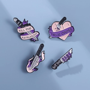 Set di spille smaltate gotiche con pugnale viola, cuore e slogan su sfondo lilla