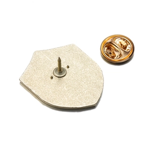 Detail of shield-shaped enamel pin back with golden butterfly clutch on white background