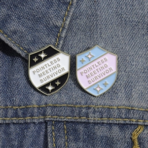 Shield enamel pins with Pointless Meeting Survivor text on blue denim jacket fabric