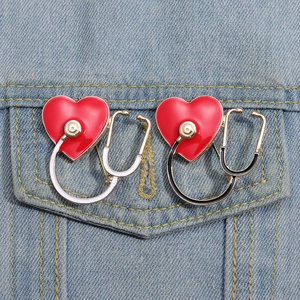 Detail of red heart stethoscope enamel pins set on denim pocket for doctors and nurses