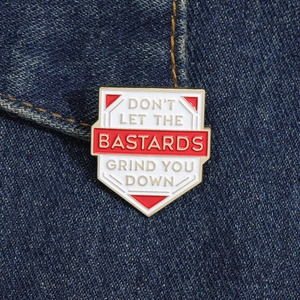 Vintage style metal shield enamel brooch with BASTARDS text on blue denim fabric