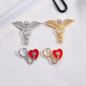Medical brooch set with stethoscope, caduceus wings and heart design in gold and silver