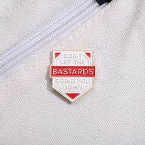 Inspirational badge brooch with Don't Let The Bastards Grind You Down text on canvas